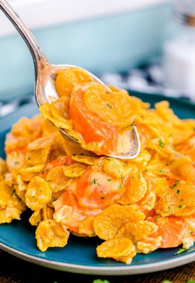 Close up photo of carrot casserole being scooped onto a blue plate.