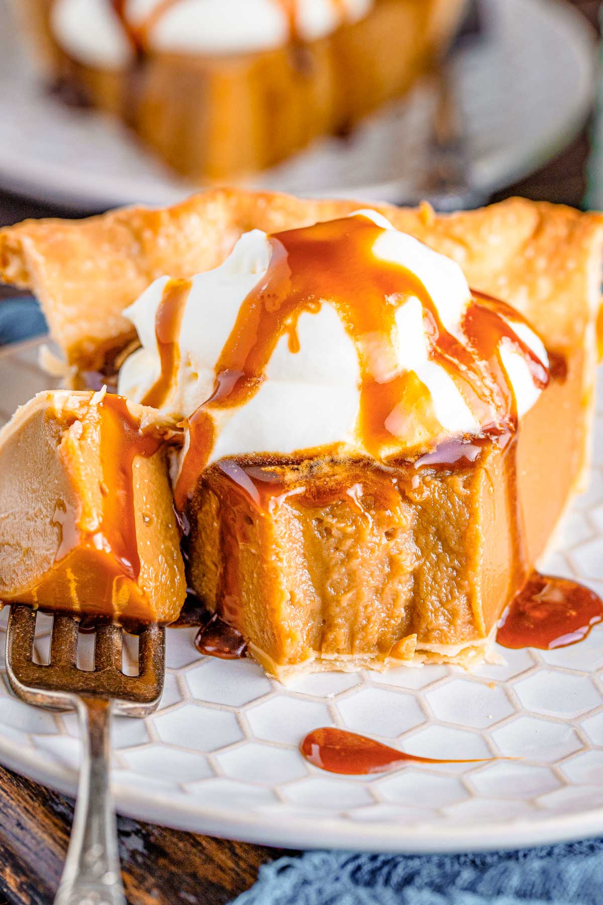 Close up photo of a slice of butterscotch pie on a white plate with a bite taken out of it and the fork next to it on the plate.