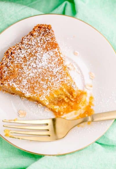 A slice of Crack Pie on a white plate on a green napkin with a fork.