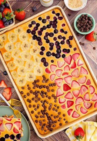 Overhead photo of sheet pan pancakes on a wooden table with 4 different flavors.