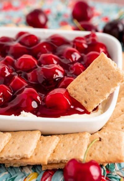 Close up photo of cherry cheesecake dip with graham crackers around the bowl and one sticking out of it.