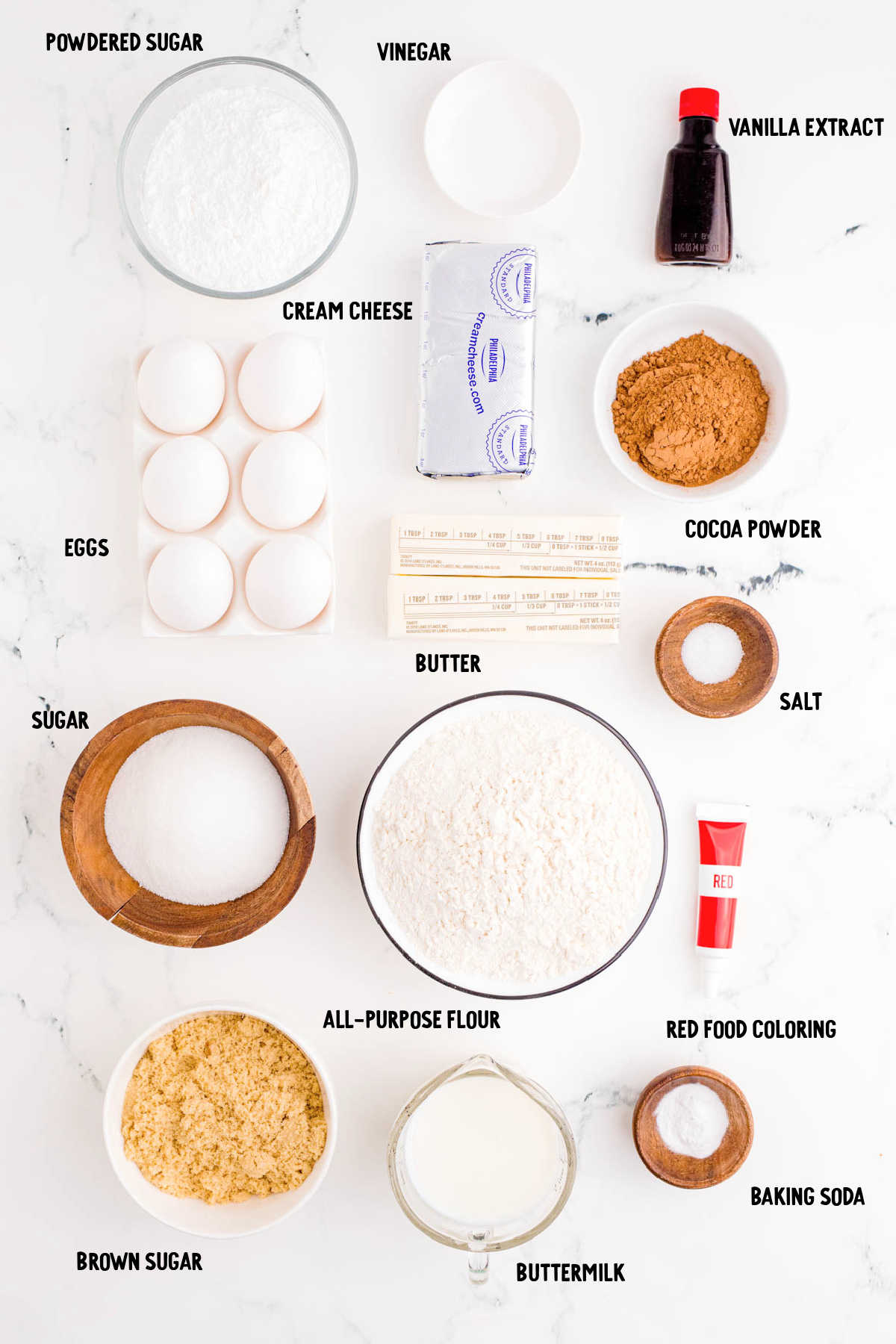 Ingredients to make red velvet whoopies pies prepared on a marble counter.