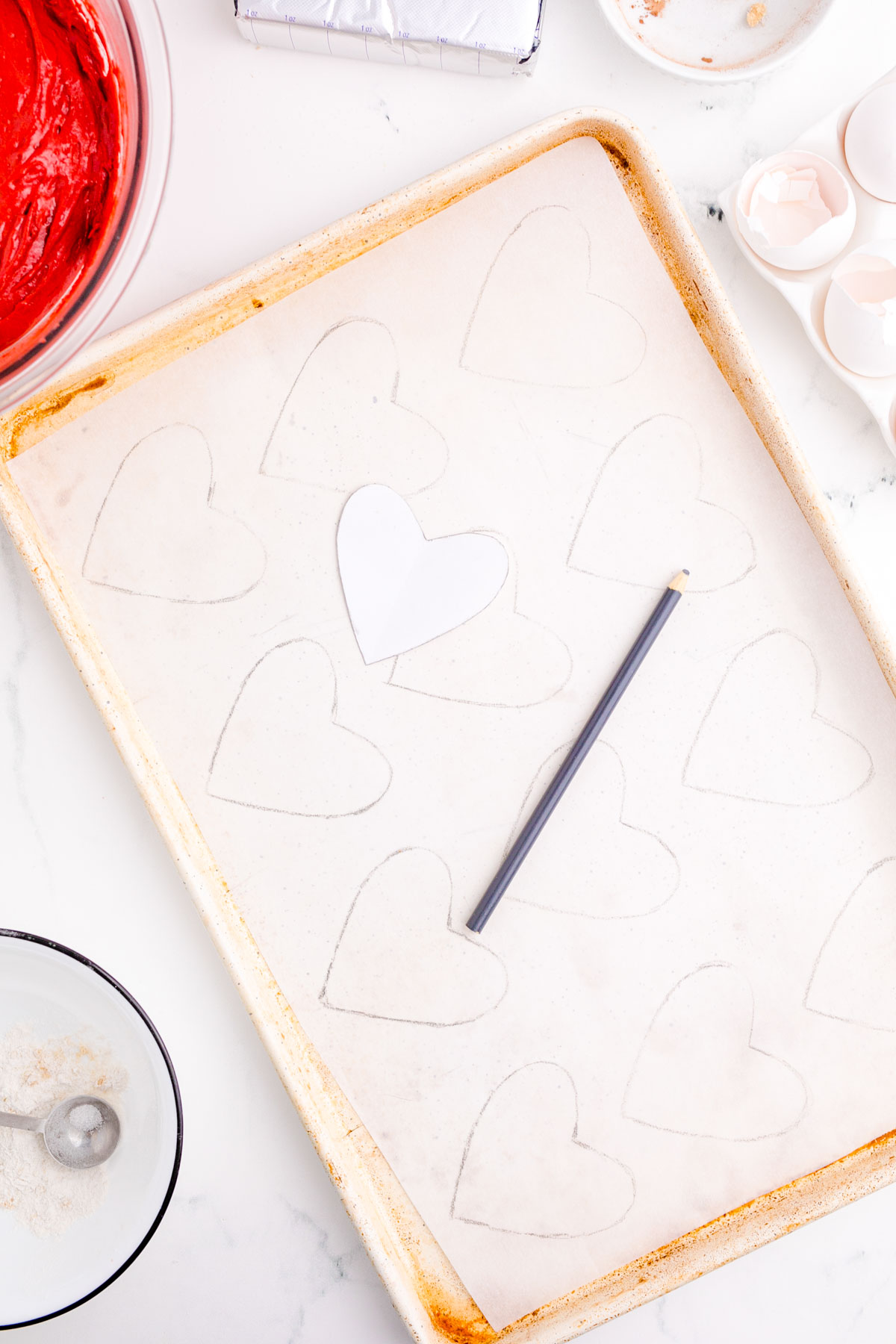 Hearts being stenciled onto parchment paper on a cookie sheet to make whoopie pies.