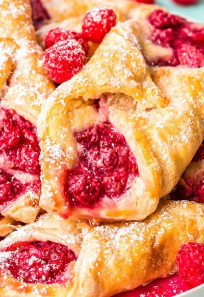 Close up photo of raspberry danishes piled on a plate.