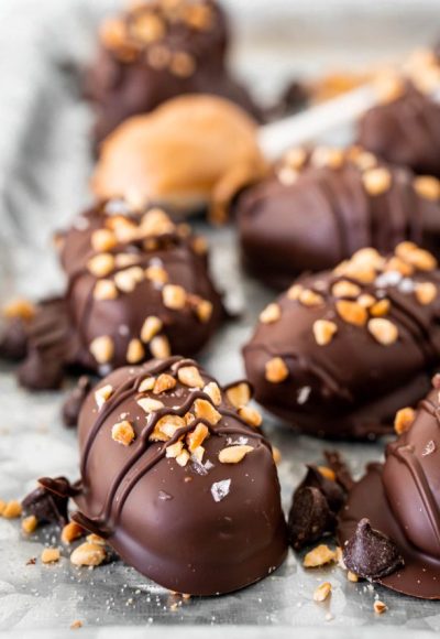 Close up photo of chocolate covered dates topped with chopped peanuts and flaky salt.