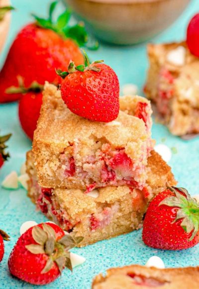 Close up photo of two strawberry blondies stacked on top of each other on a blue surface.