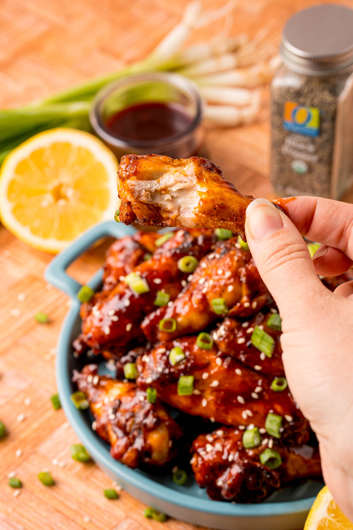 A woman's hand holding up a chicken wing with a bite missing.