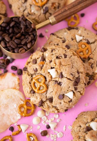 Compost cookies on a pink surface with ingredients around it.