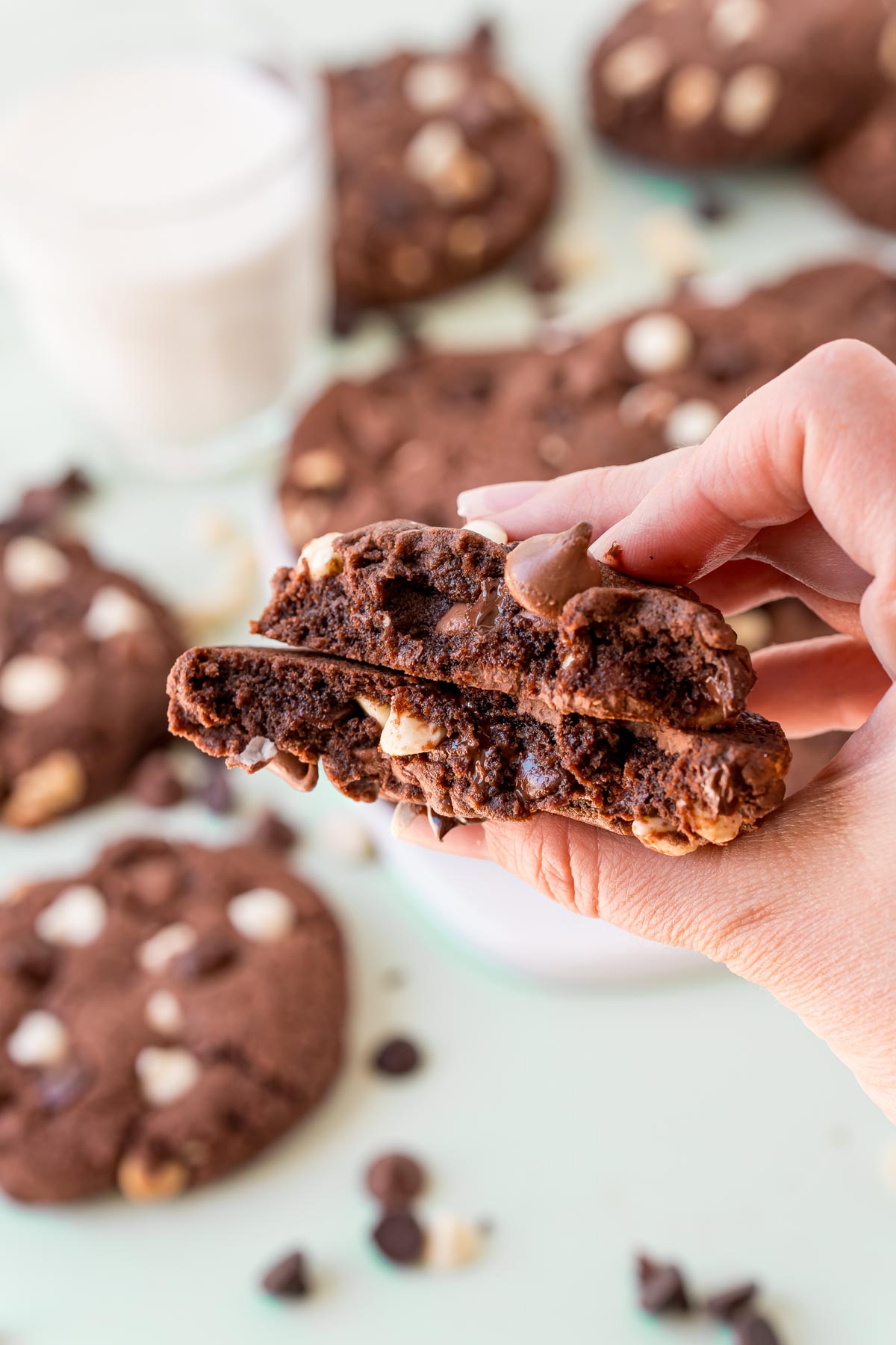 Triple chocolate cookie that's been brown in half and a hand is holding it to show the interior.