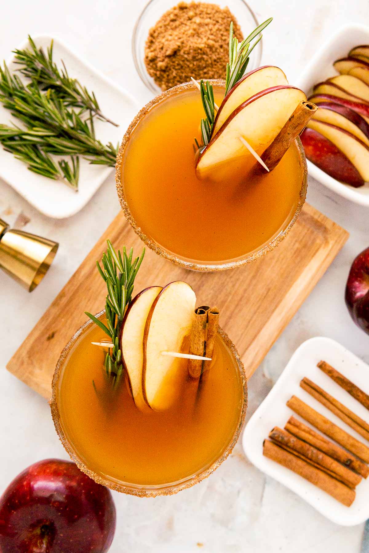 Overhead photo of two coupe glasses filled with apple cider bourbon cocktails.