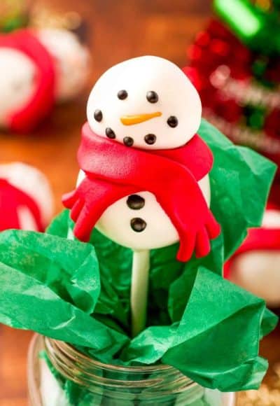 Snowman cake pop in a mason jar with green tissue paper.