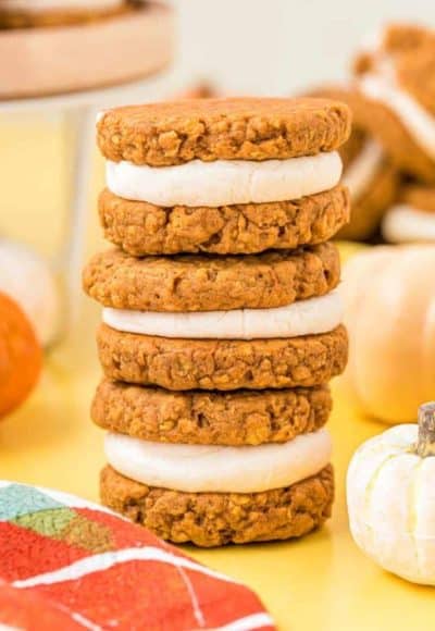 A stack of three pumpkin oatmeal creme pies on a yellow table.