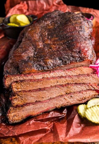 A smoked brisket that's been partially sliced on paper.