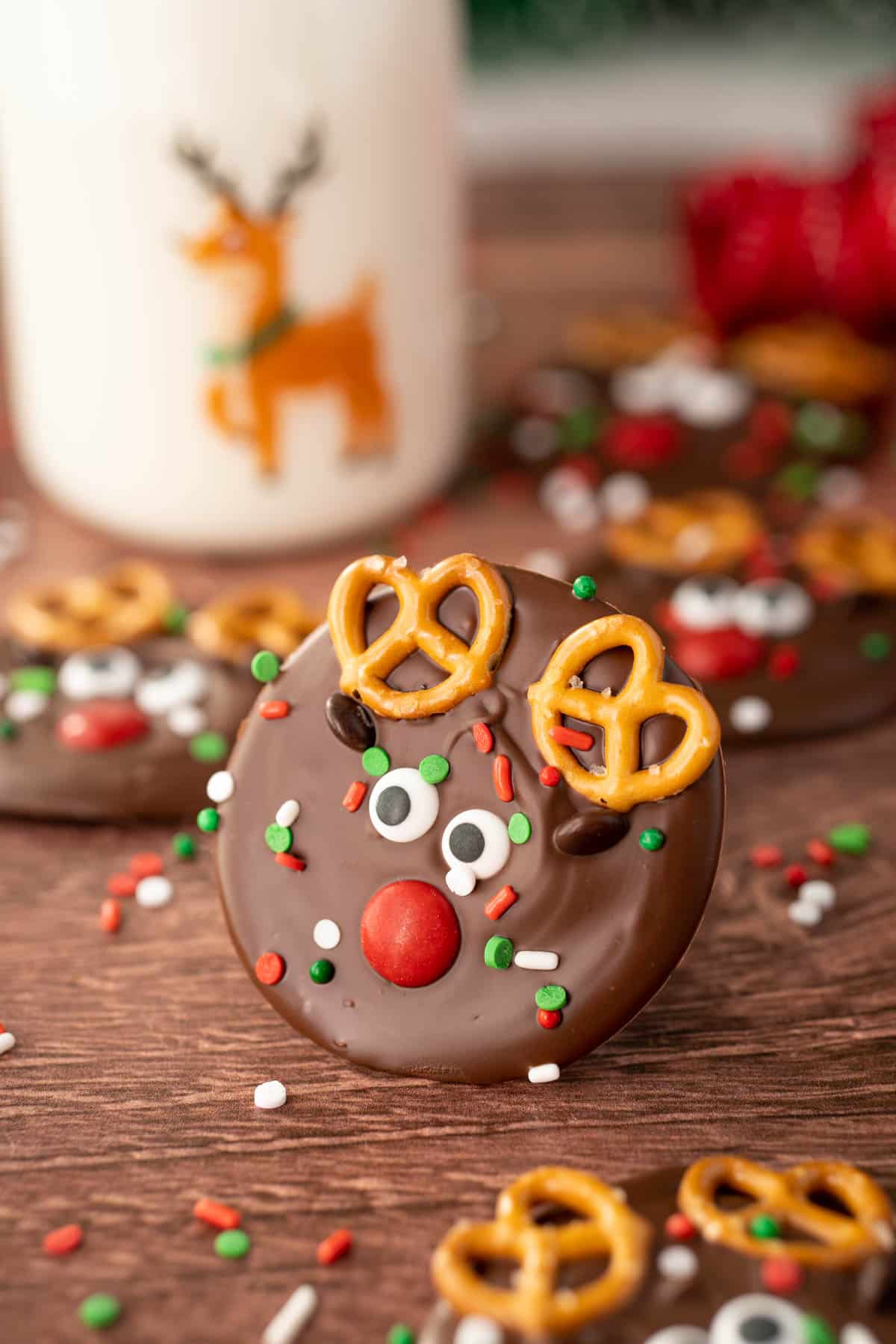 A piece of christmas bark decorated as a reindeer on a wooden table with more in the background.