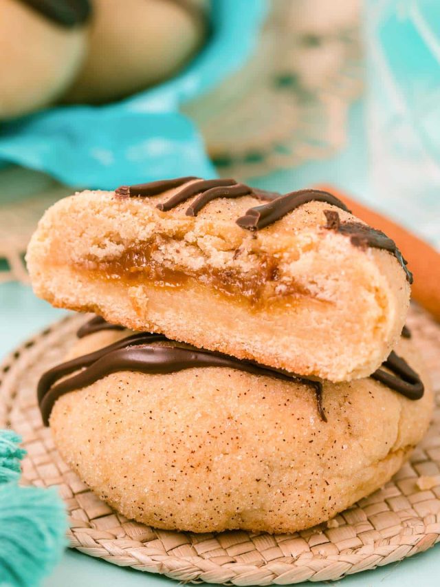 Two cookies stacked, one sliced open revealing the center stuffed with dulce de leche.