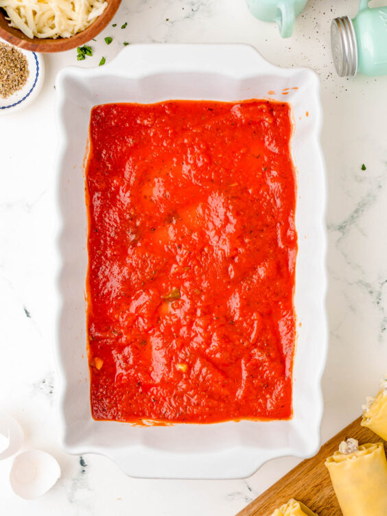 Marinara sauce in the bottom of a baking dish.