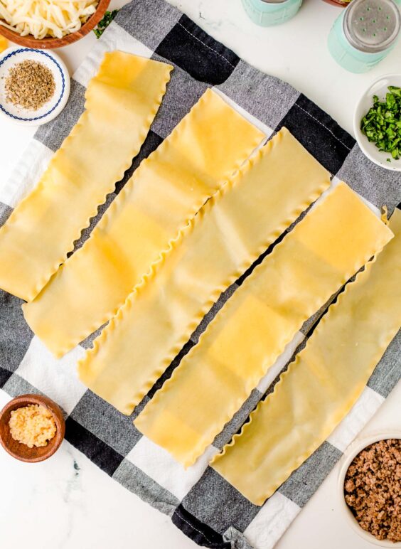 Cooked lasagna noodles on a kitchen towel.