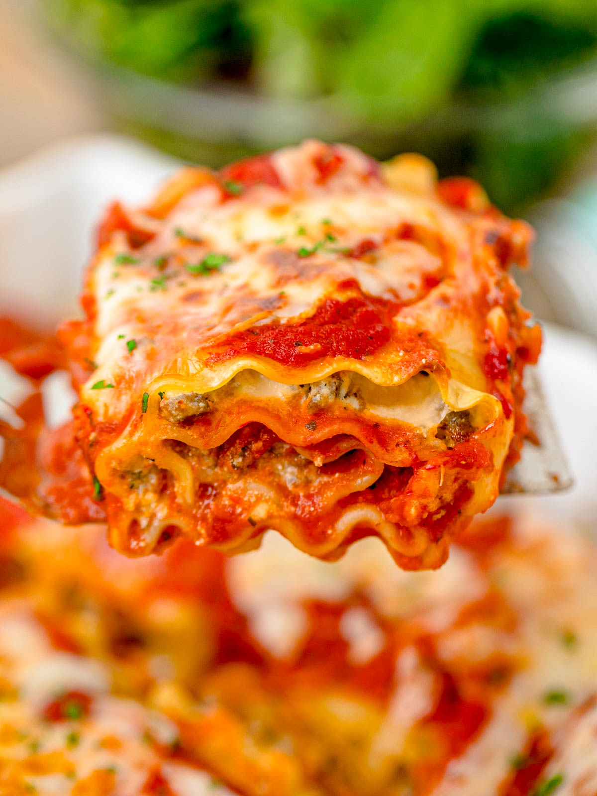 Close up of a lasagna roll-up on a spatula being lifted out of a pan.