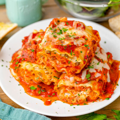 A plate of lasagna roll-ups ready to be eaten at a table.