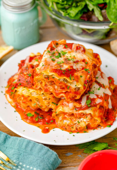 A plate of lasagna roll-ups ready to be eaten at a table.