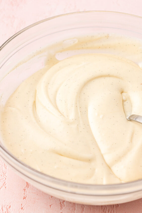 Cream cheese icing in a glass mixing bowl.