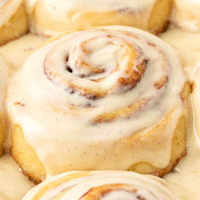 Close up of iced cinnamon rolls on a pan.