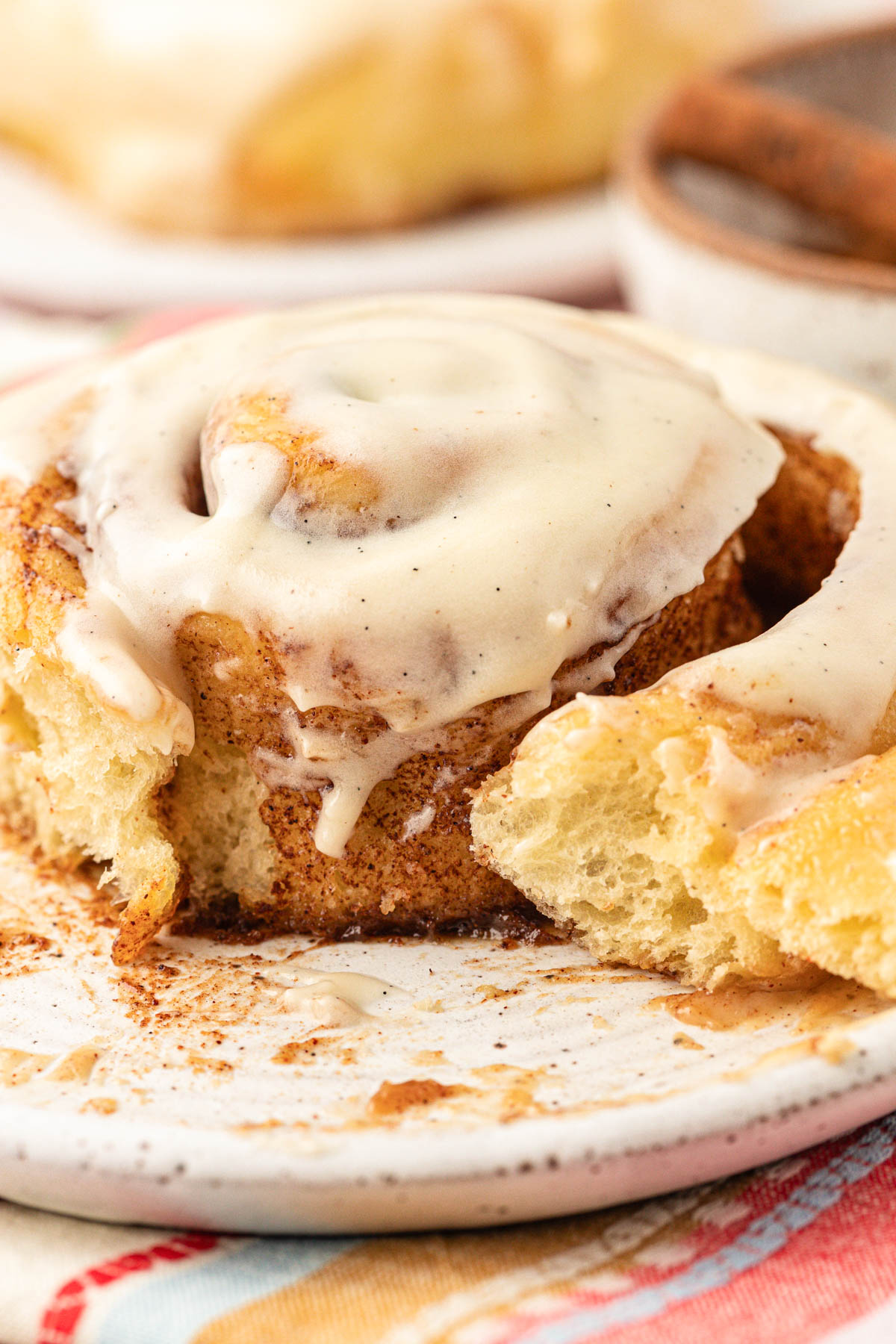 Close up of Amish potato cinnamon rolls on a plate with a bite missing.