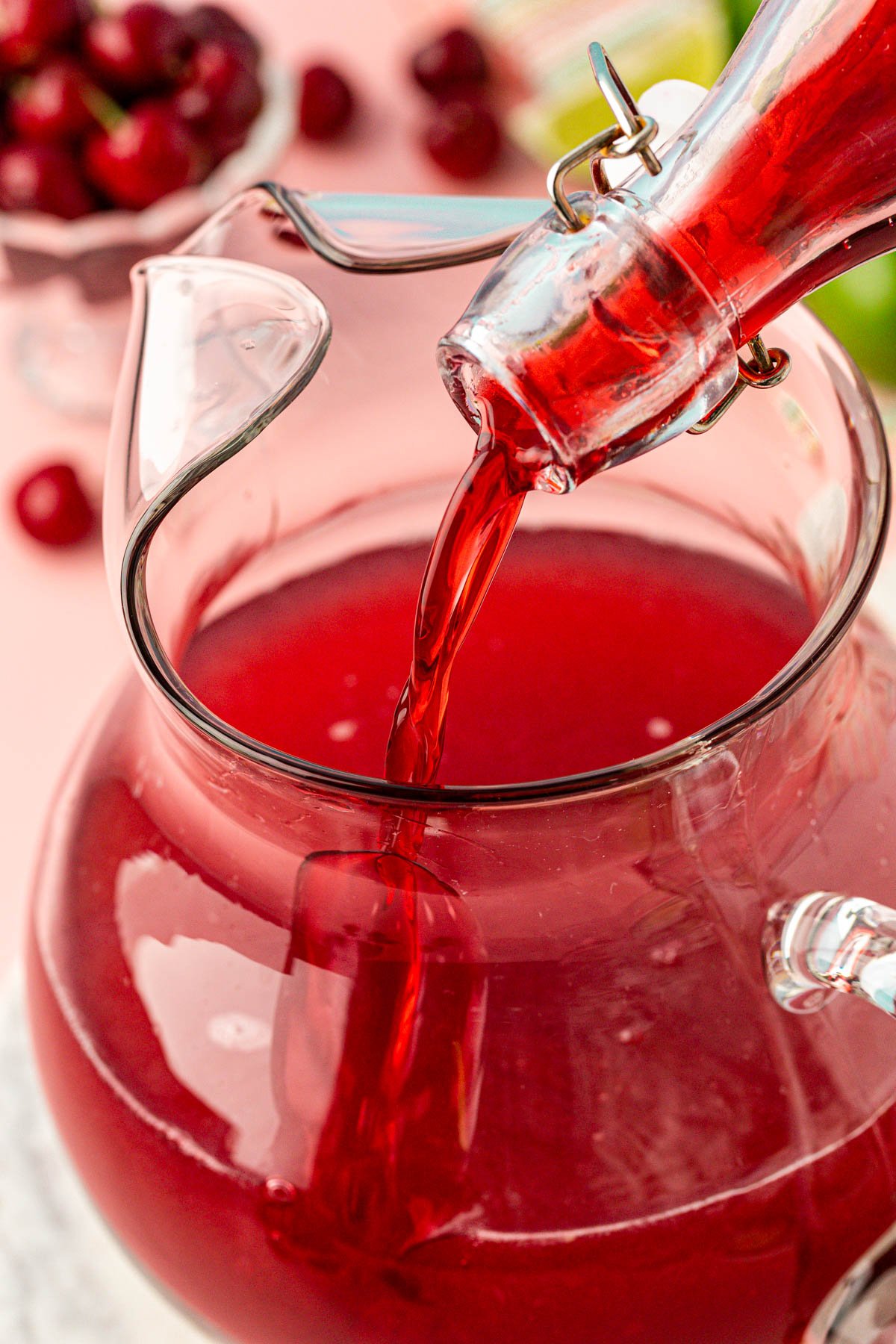 Cherry simple syrup being poured into a pitcher.