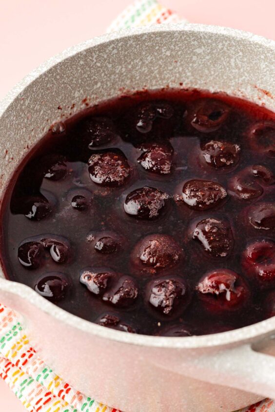 Cherries, sugar, and water in a pot to make syrup.