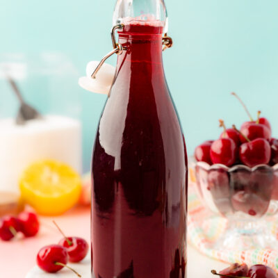 A bottle of cherry simple syrup on a table.