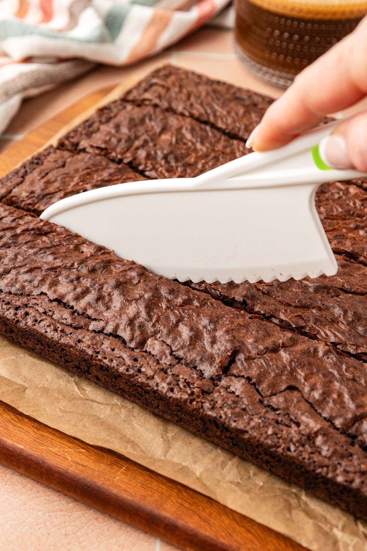 A plastic knife cutting brownies on a cutting board.