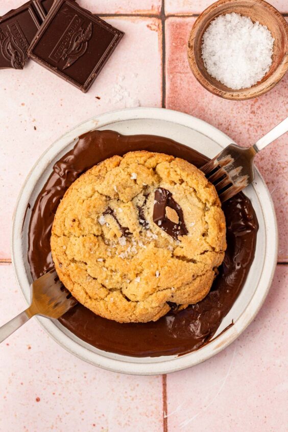 Forks dipping a chocolate chip cookie in chocolate like Jacques Torres recipe.