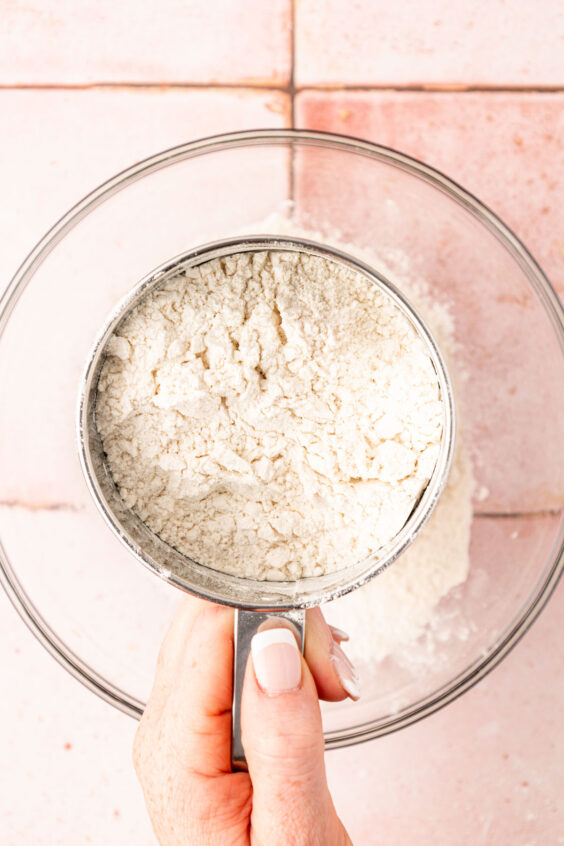 Flour being sifted into a glass bowl.