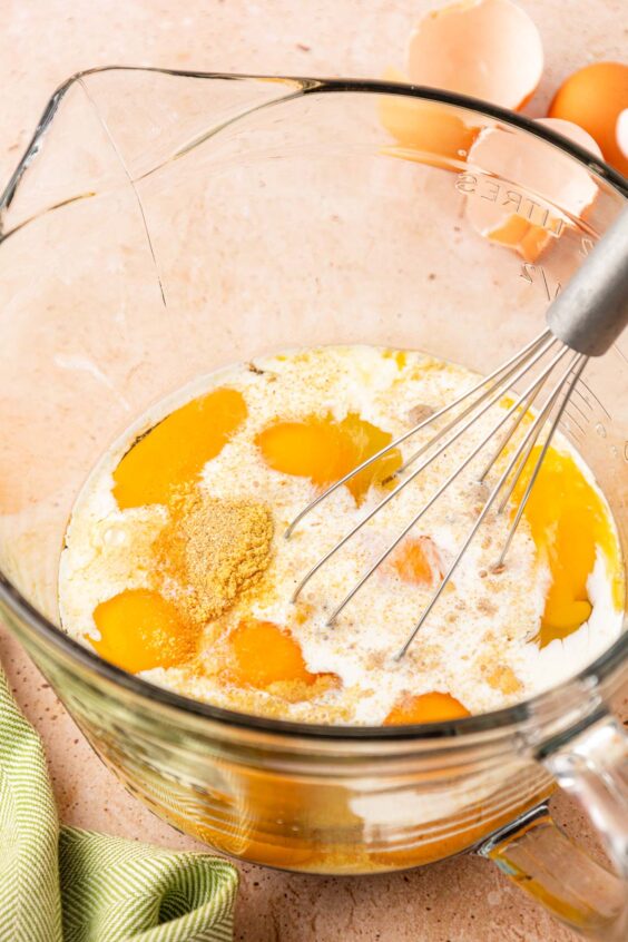 Eggs, cream, and seasonings being whisked in a mixing bowl.