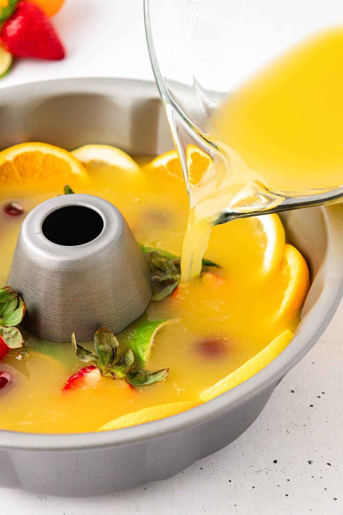 Punch being poured into a bundt pan with fruit.