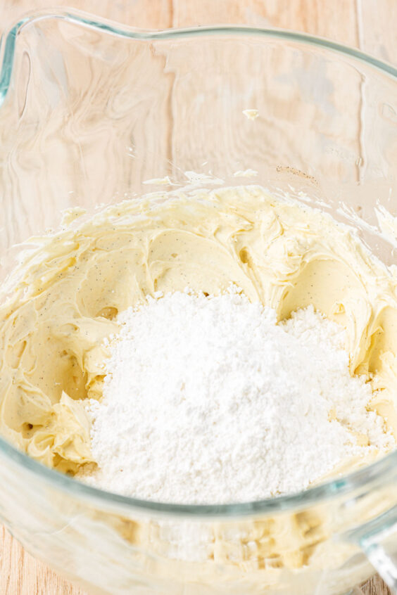 Powdered sugar being added to a bowl to make frosting.