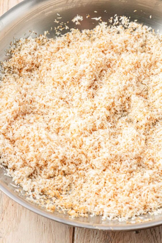 Shredded coconut being toasted in a skillet.