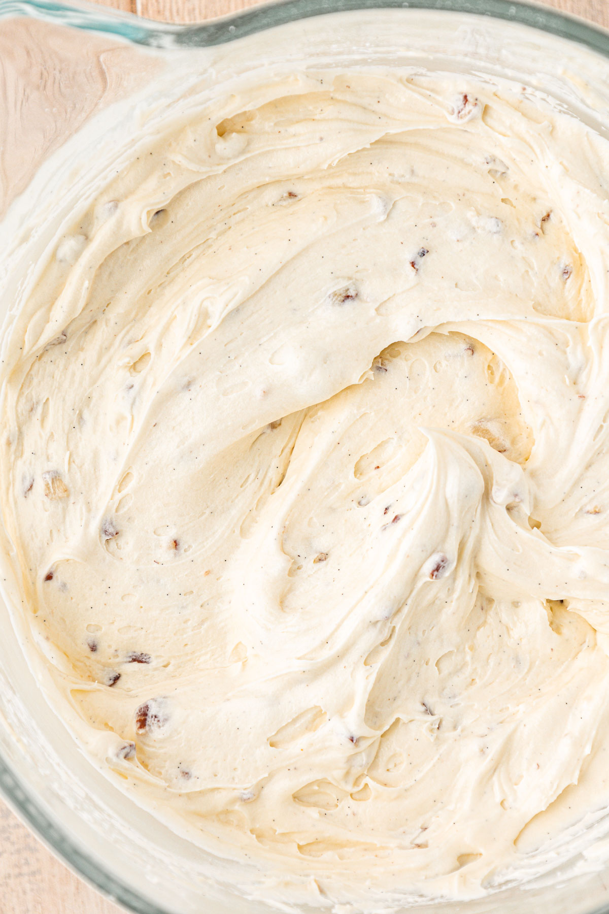 Overhead of cream cheese frosting with pecans in it.