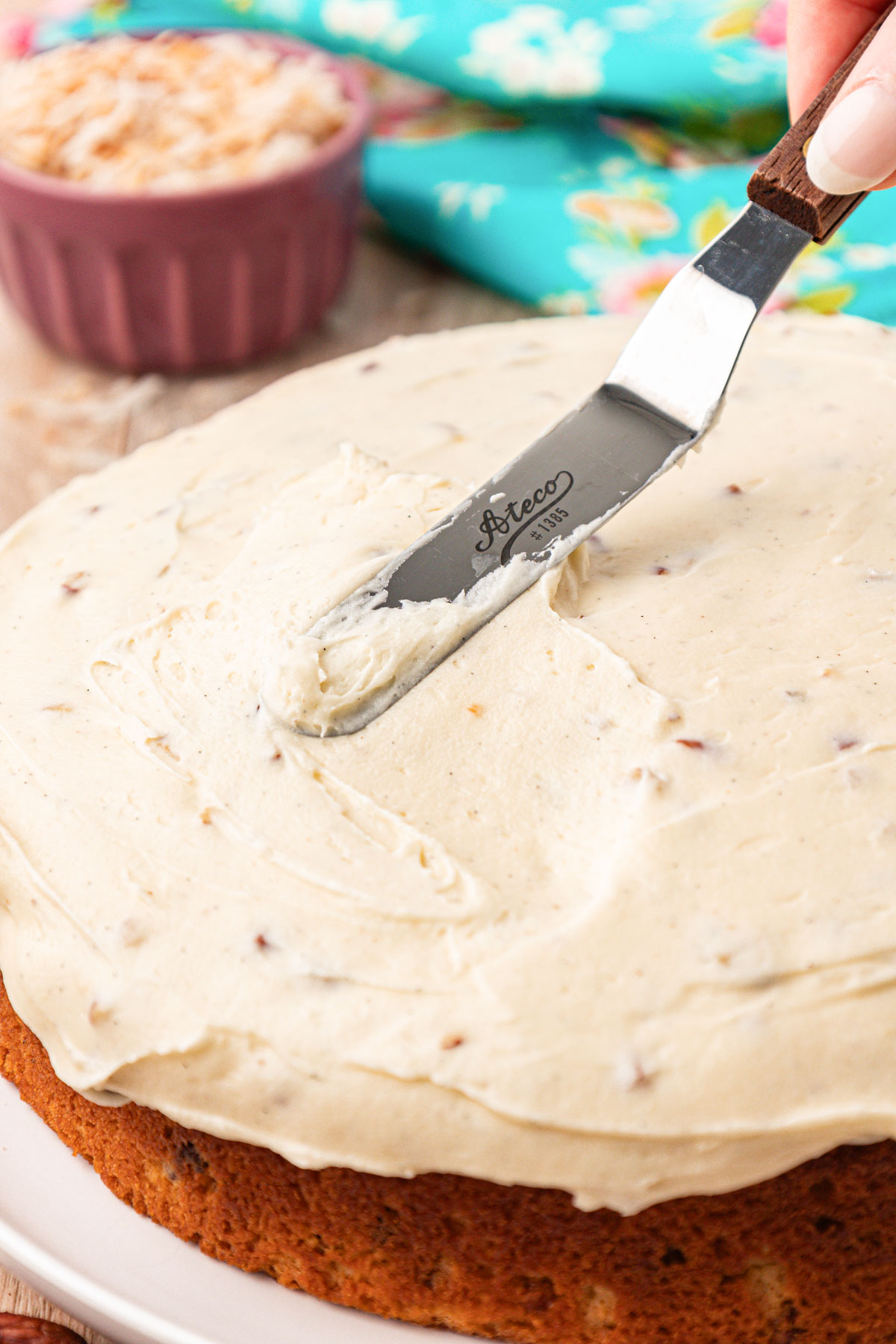 Frosting being spread on a round layer cake.