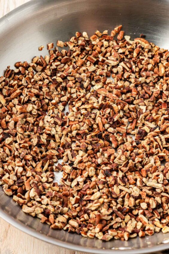 Pecan chips being toasted in a pan.