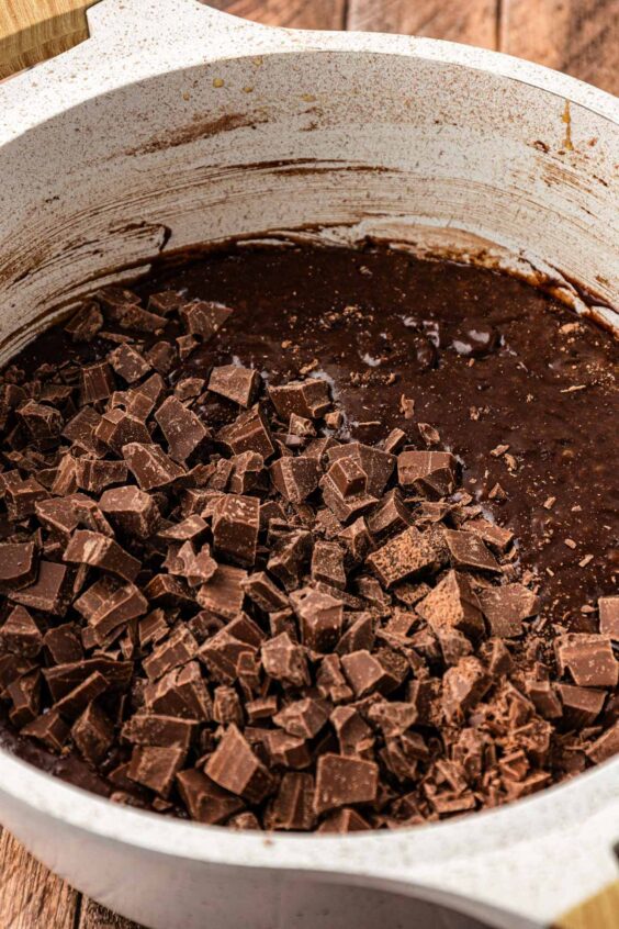 chopped chocolate being added to a pot with brownie batter.