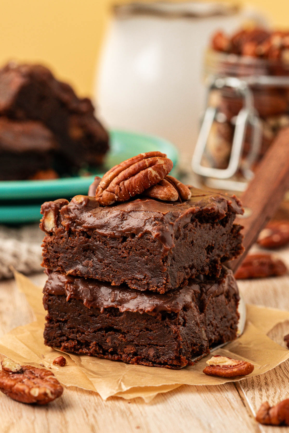 Two Texas Sheet Cake Brownies stacked on a piece of parchment on a table.