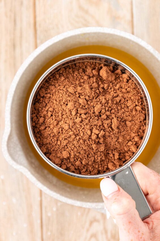 Powdered sugar and cocoa powder being sifted into a pot.