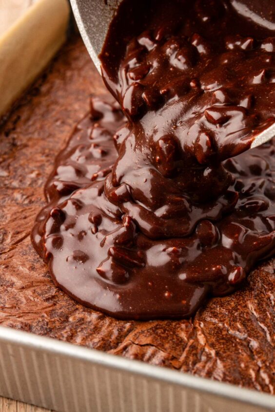 Texas Sheet Cake Icing being poured on brownies in a pan.