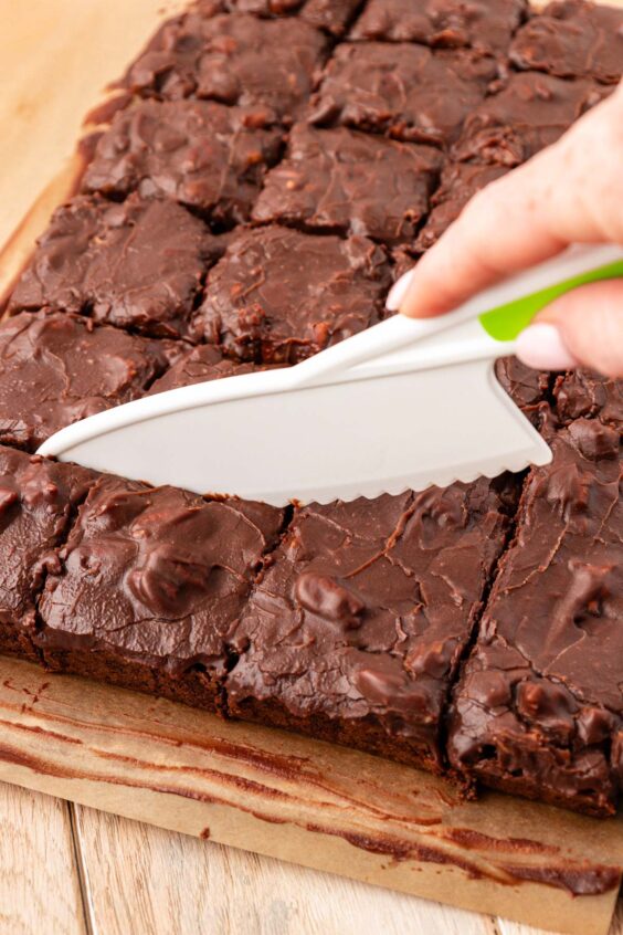 A plastic knife slicing through texas sheet cake brownies.