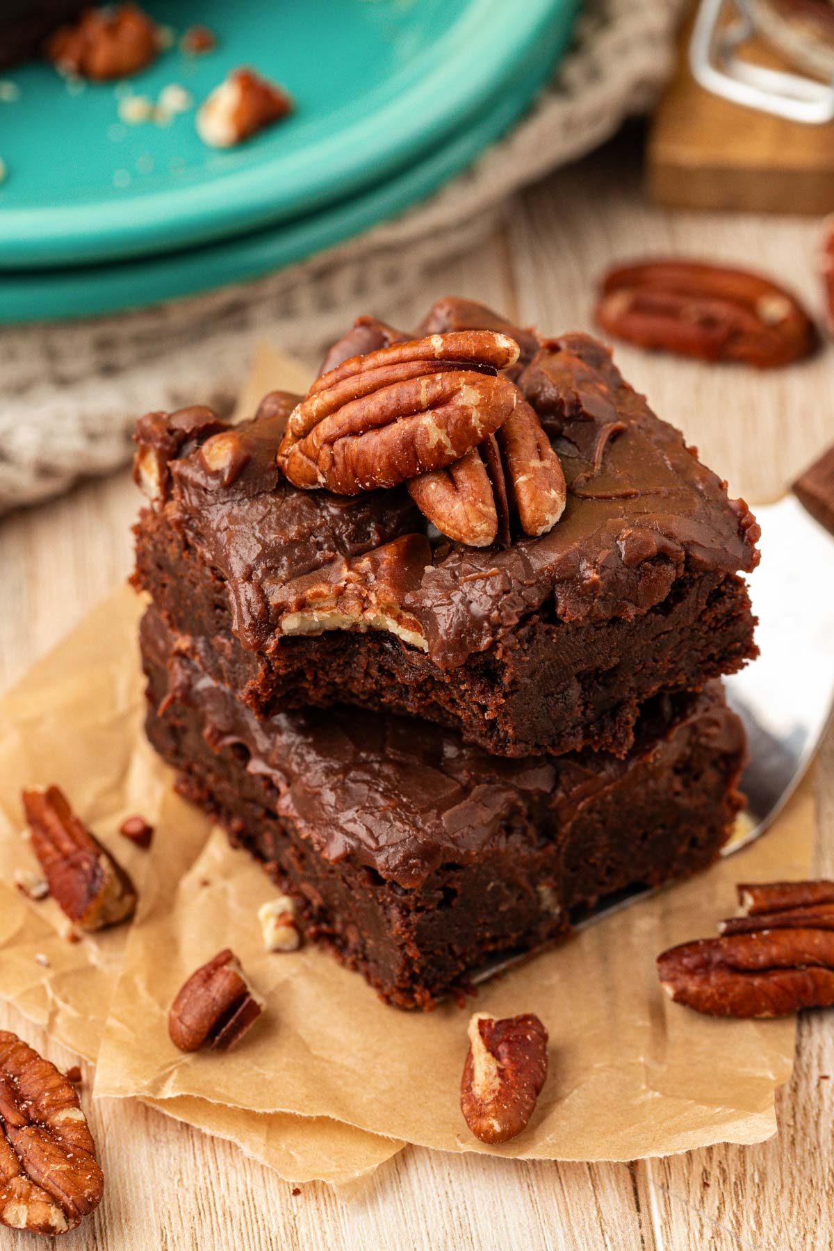 A stack of two iced brownies on a piece of parchment.