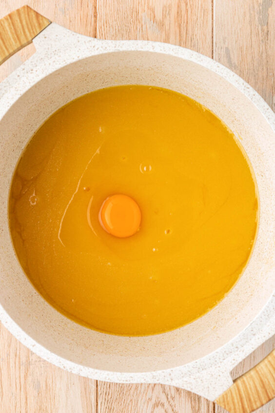 Egg being added to a pot with butter and sugar.