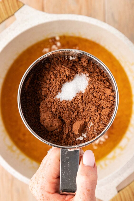 Flour and cocoa being sifted into a pot of butter and sugar.