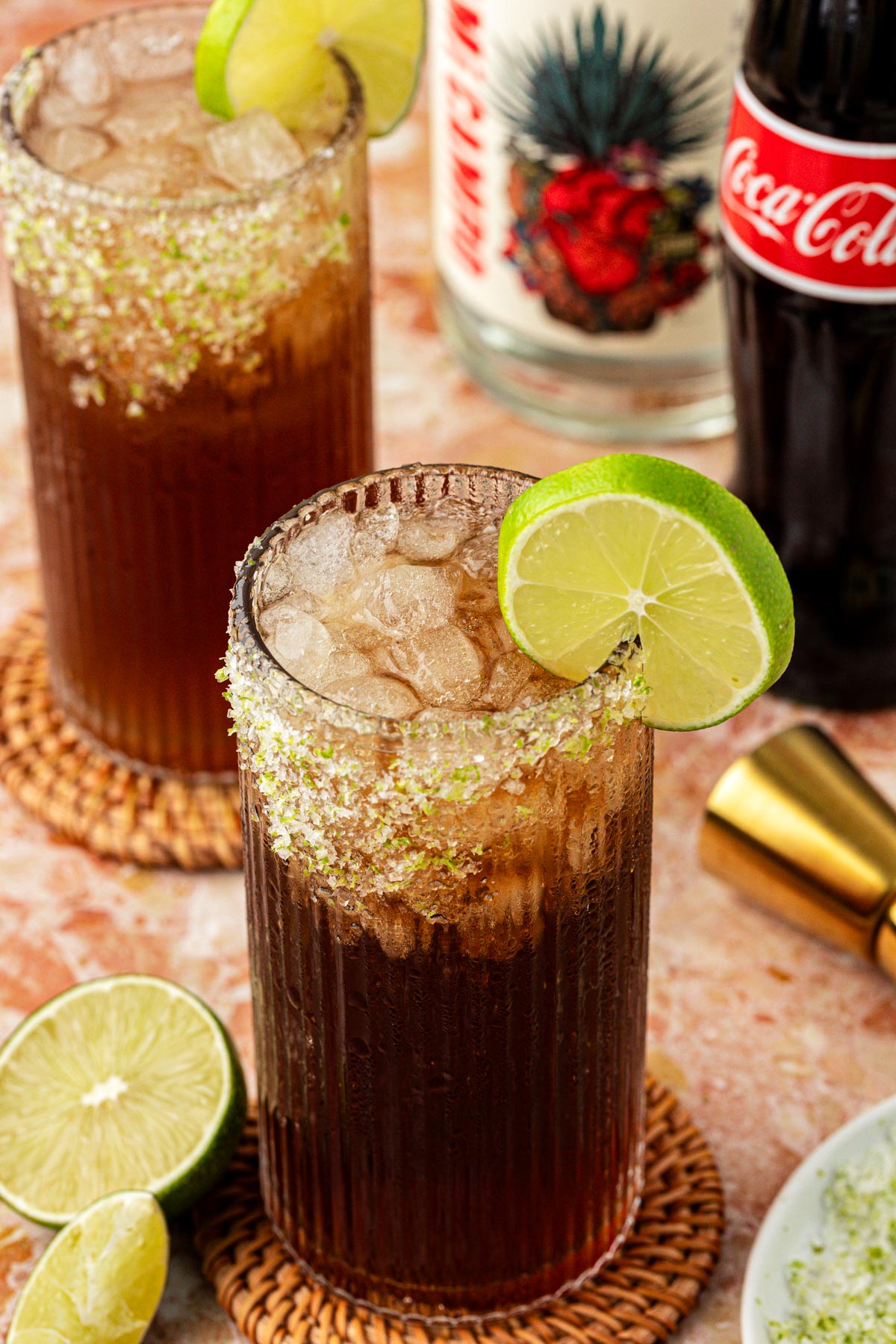 Two Batanga cocktails garnished with a lime wheel on a table.