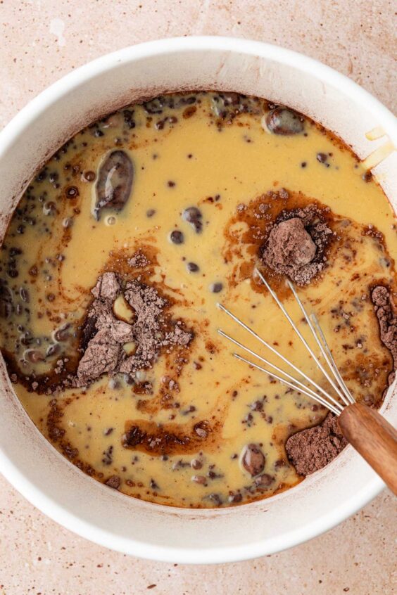 Wet ingredients poured into dry ingredients in a bowl to make chocolate muffins.